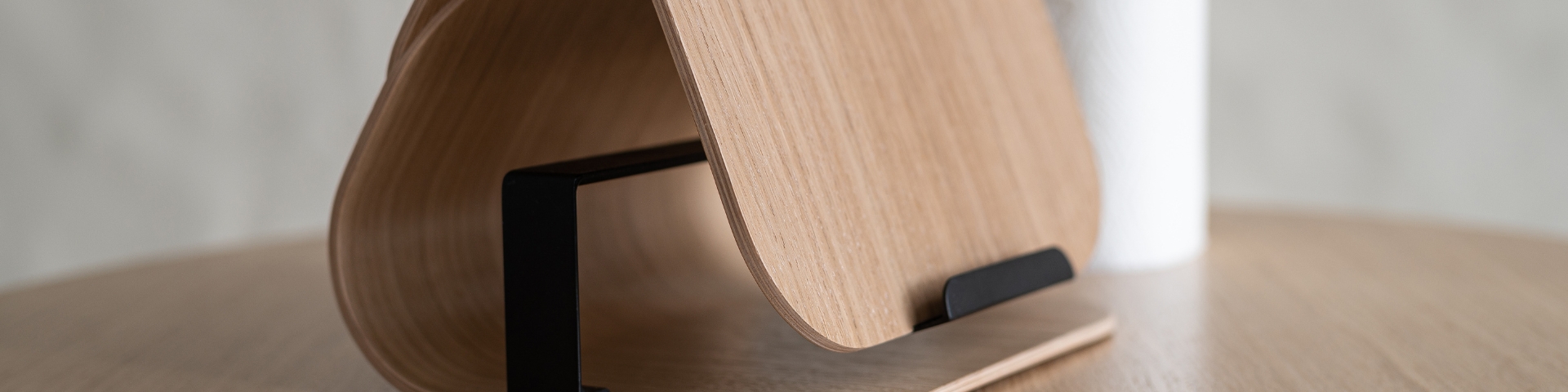 PILOT wall-mounted kitchen roll holder by Plydesign – smooth plywood form hides roll, with extended support bar for easy dispensing in walnut, oak or pastel shades.