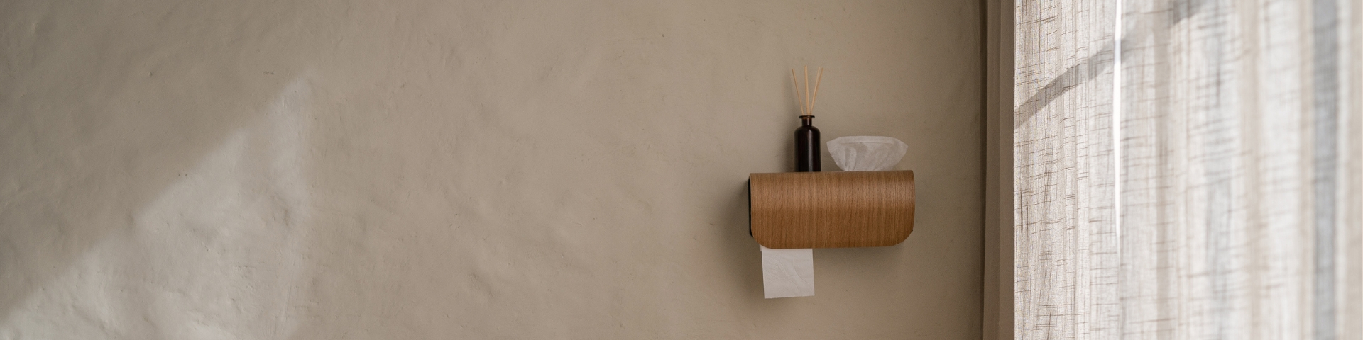 CAPTAIN wall-mounted toilet roll holder with curved wooden frame—compact, durable design that blends subtle elegance with daily practicality.